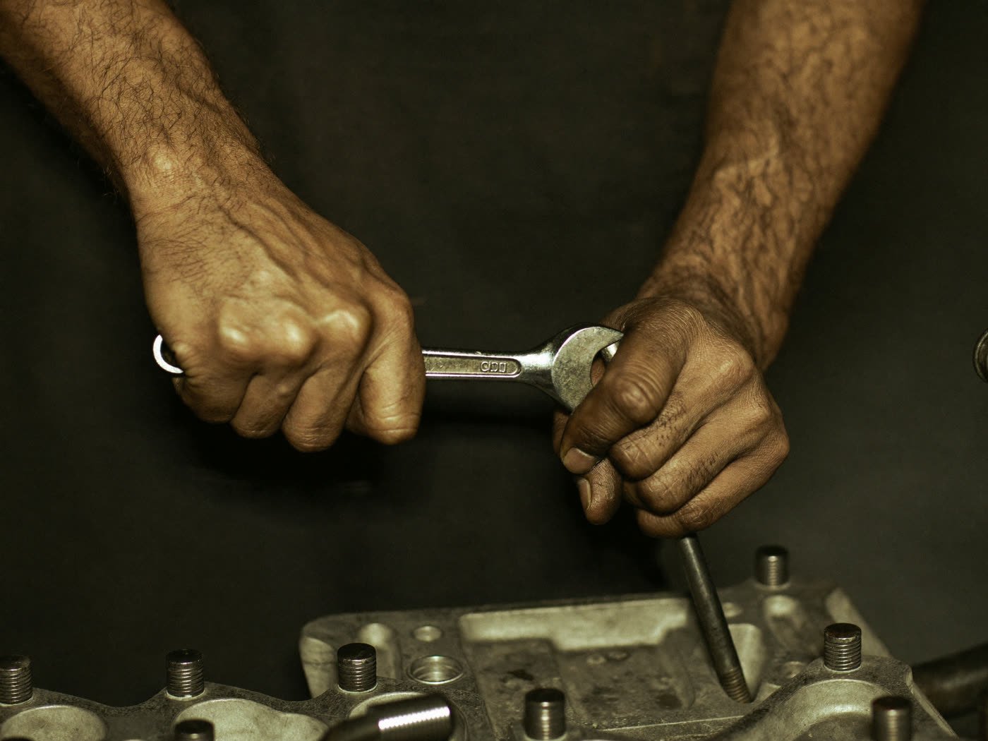 Manos de un mecánico ajustando el motor con una llave