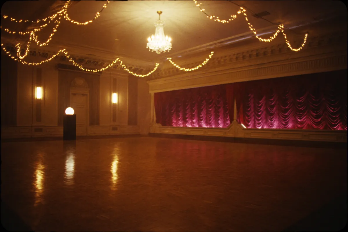 Pista de baile de Villa Aurelia con cortinas bordó, luces cálidas y araña de cristal